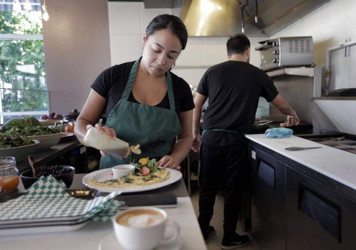 Yurmir Gonzalez, left, puts the finishing touches on a recently prepared omelette at La Social as Robson Gonzalez warms the whole grain bread to go with it.