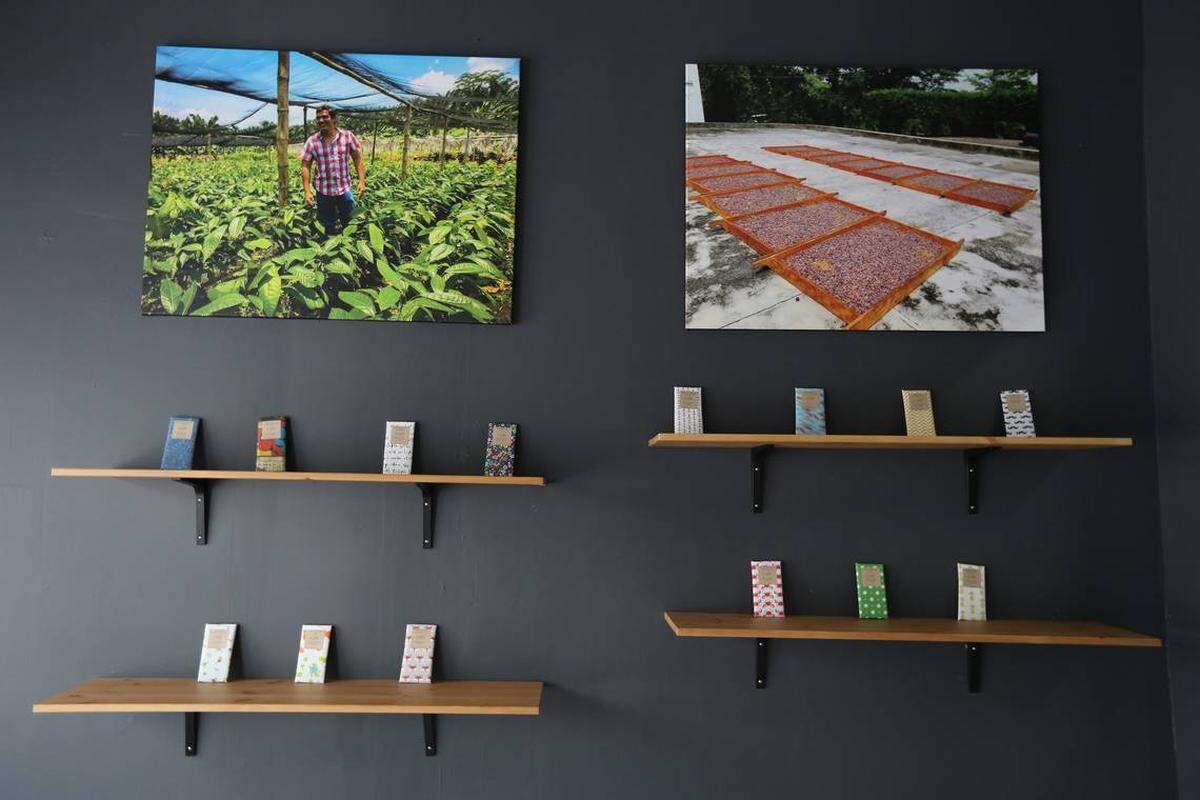 Handmade and handwrapped chocolate bars line the shelves in the lobby of the factory underneath photos of the farms where some of the cocoa beans are purchased.
