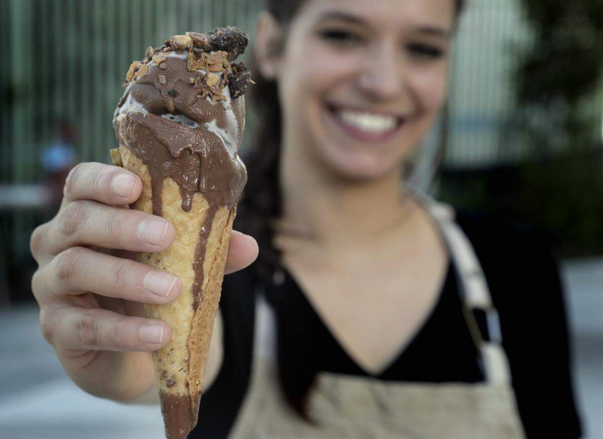 Devin Braddock holds up her version of Drumstick: brown butter waffle cone, rosemary ice cream, pistachios, Valrhona dulcet chocolate. It's one of the reimagined treats she makes for Tricycle Ice Cream.