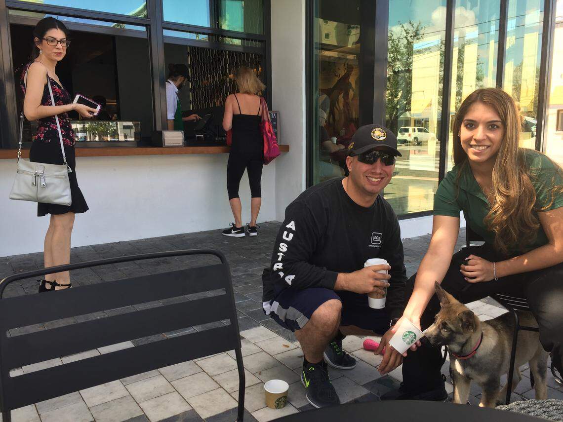 Elizabeth Jimenez and Brandon Whitice feed a whipped cream Puppuccino to Rayna outside the new ventanita at the Miracle Mile Starbucks.