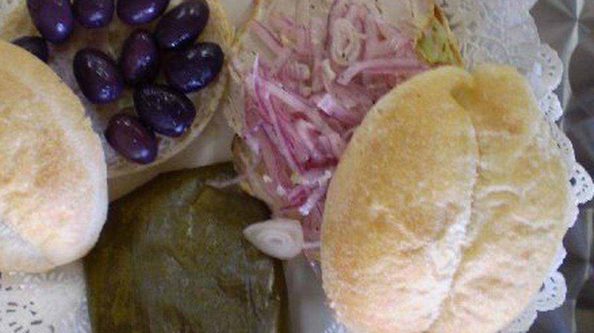 Bread, black olives, pork sandwiches and tamales.