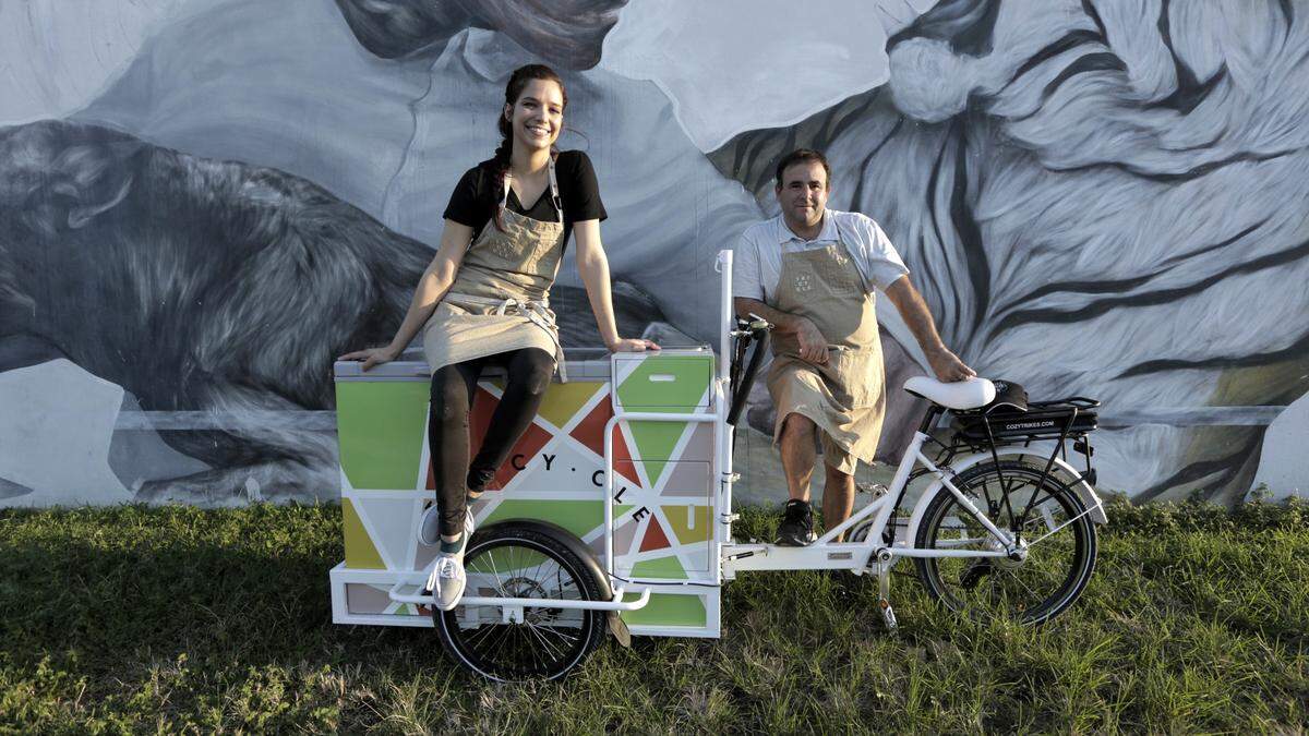 Devin Braddock and Danny Serfer with their Tricycle in front of a mural in Wynwood.