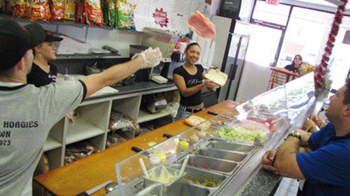 Laspada’s meat tosser Mike Lenz chucks salami to employee Jen Garcia as customers watch. Photo: Kyle Teal