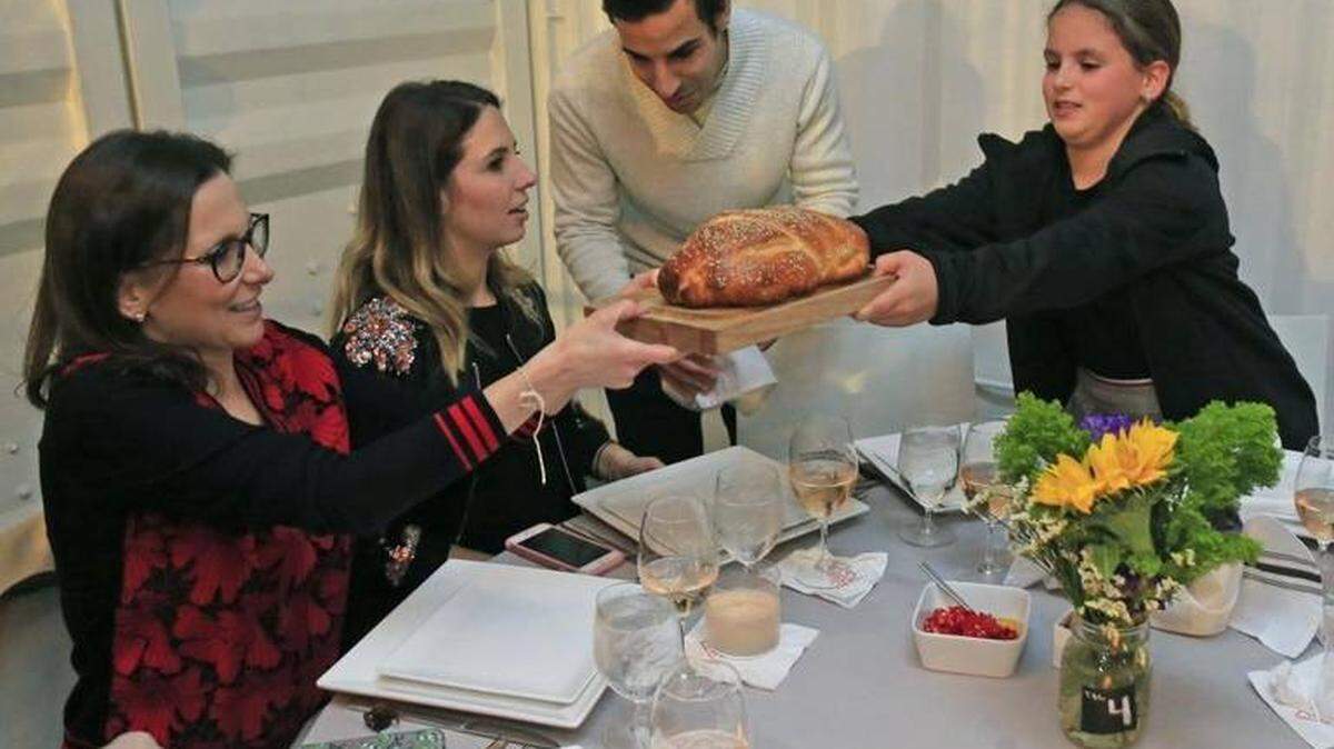Karina Krulig, Romina Krulig-Vaisberg, Yoel Vaisberg and Sara Gelrud, 11, pass a loaf of bread during Shabbat dinner at Wynwood Yard on Saturday, January 20, 2018. Several restaurants in Miami have started to offer communal dinners for what, traditionally, has been a holy and traditional Jewish meal eaten with family or after temple to mark the start of the Sabbath on Friday night. The dinners are not kosher. Instead, these shabbat meals are about community, bonding over a meal.