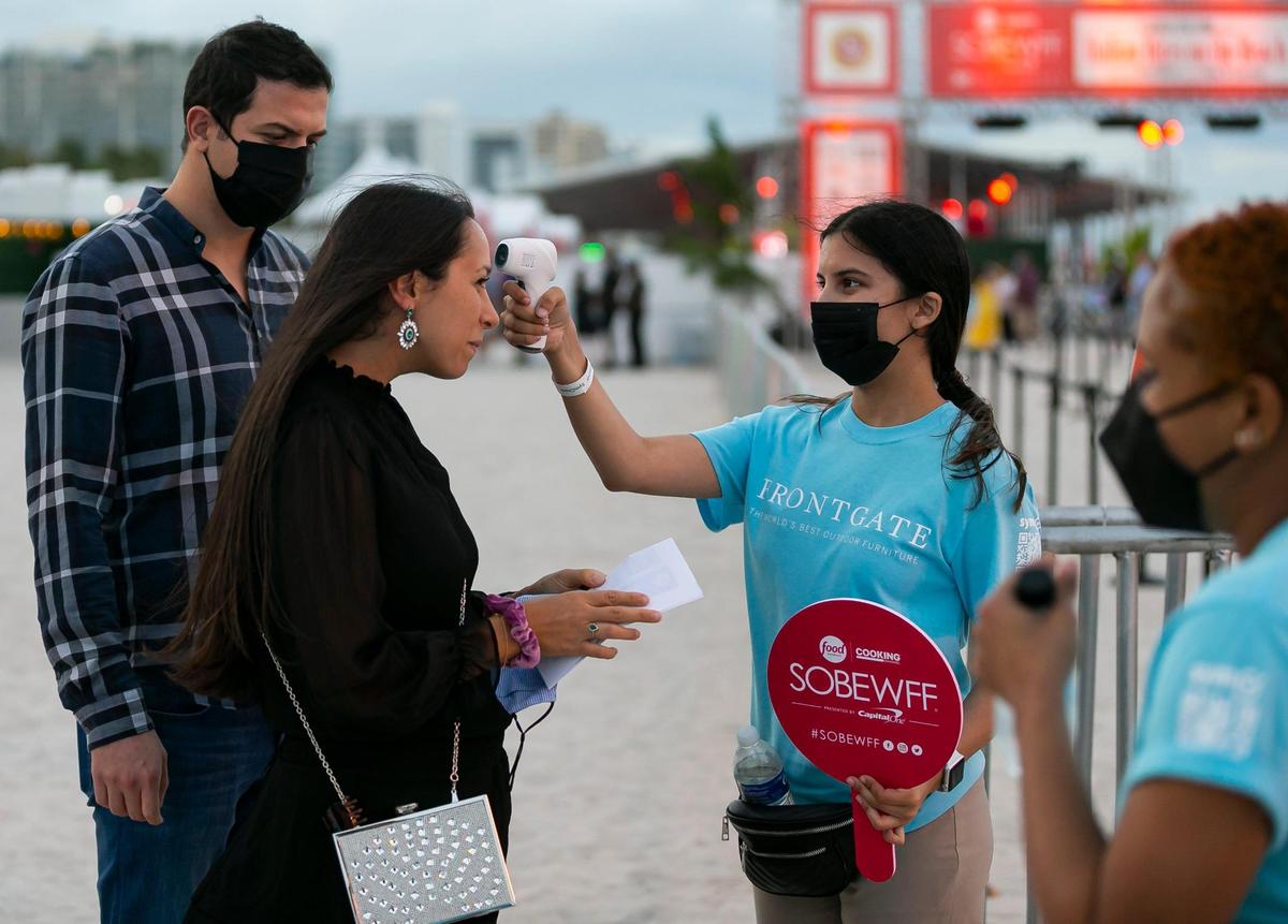 Kelly Mahoney, a Florida International University volunteer, temperature checks guests as they arrive to the South Beach Wine and Food Festival Italian Bites on the Beach.