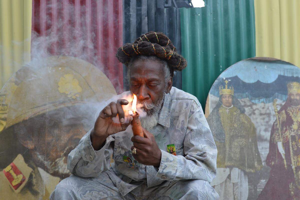 In this Aug. 28, 2014 photo, legalization advocate and reggae legend Bunny Wailer smokes a pipe stuffed with marijuana during a reasoning session in a yard in Kingston, Jamaica, decorated with Rastafarian colors and images of former Ethiopian Emperor Haile Selassie. Wailer, a founder of the iconic Wailers reggae group with late superstars Bob Marley and Peter Tosh, and fellow Rastafarians have long called for legalization of the drug that they smoke as part of their spiritual worship. Now, many Rastas are welcoming plans by the Jamaican government to decriminalize marijuana for religious purposes, among other proposed amendments to the islands drug laws. (AP Photo/David McFadden)