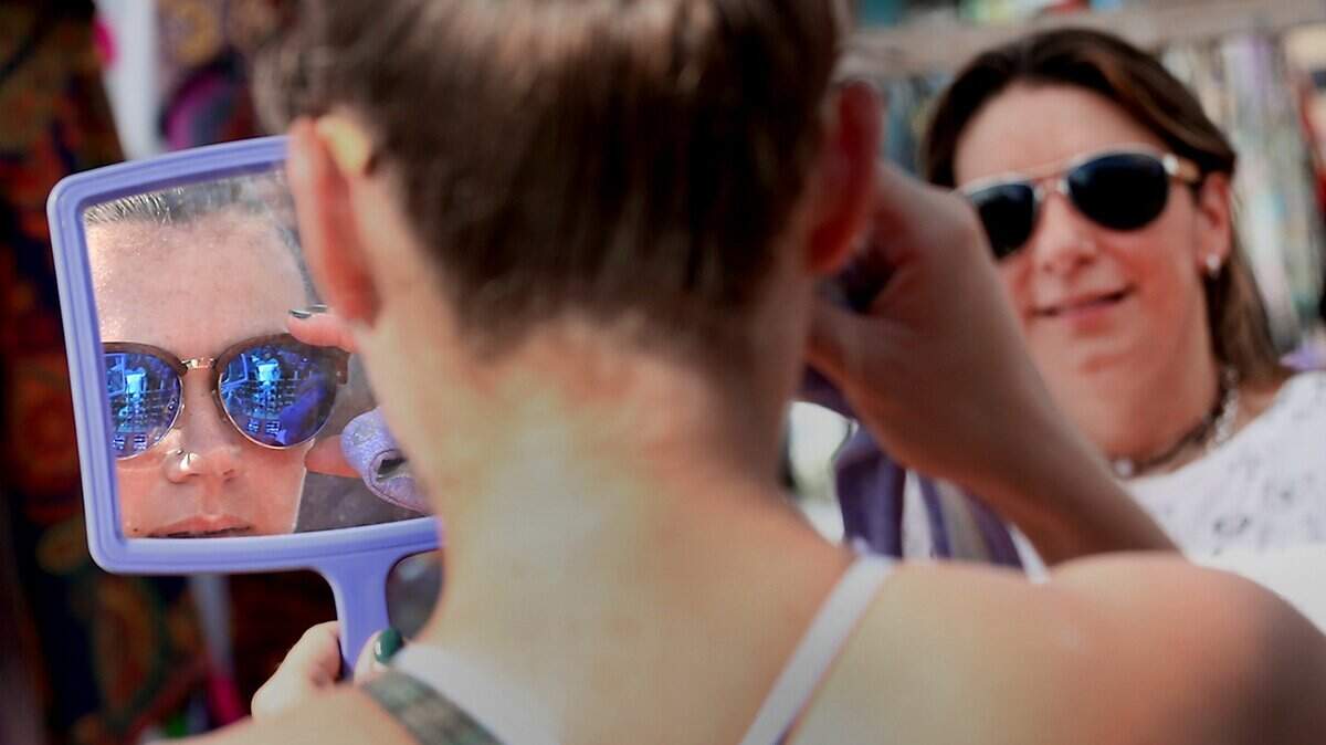 Dana Wall of Miami tries on glasses made by  Paola Lina (background) of OK4U a shoppers attend the very last Miami Flea of 2016  put on in the Arts + Entertainment District in Miami on Sunday, December 18, 2016