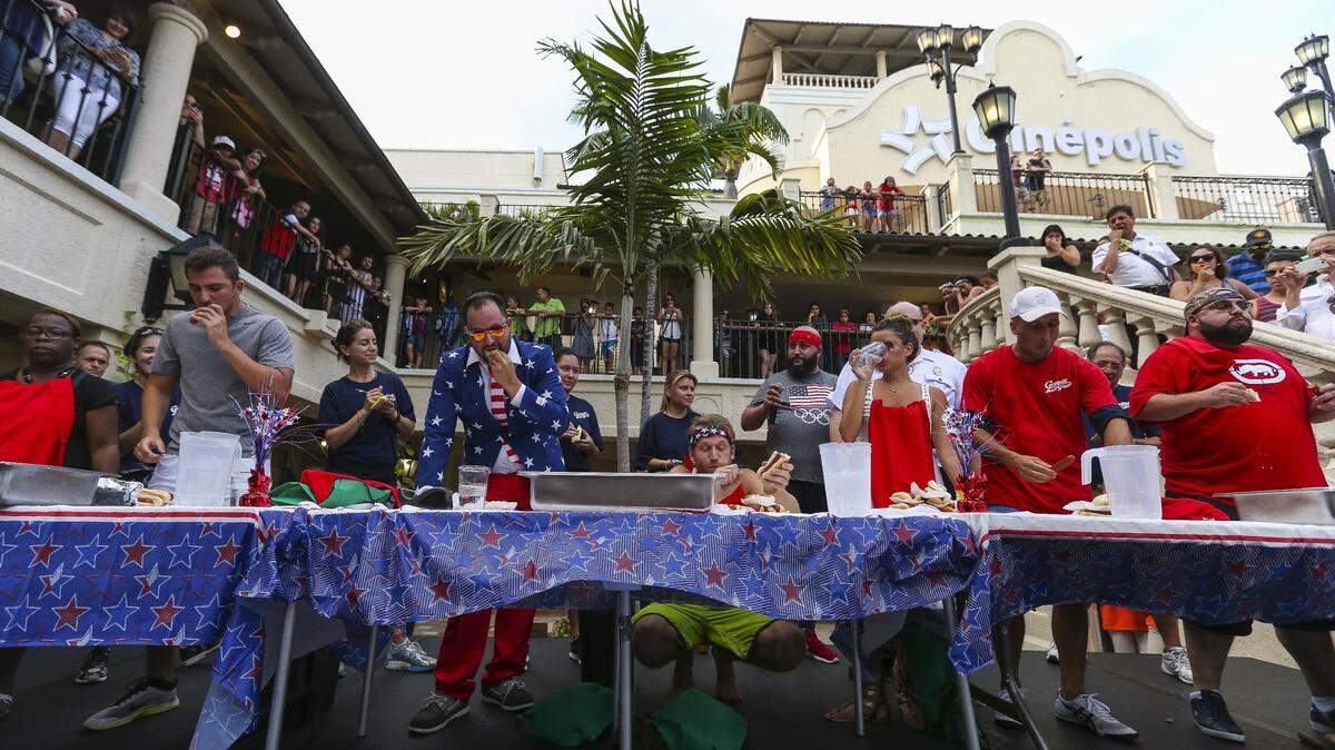 Participants compete in CocoWalk's 8th Annual Hot Dog Eating Contest to celebrate Independence Day in Coconut Grove on July 4, 2016.  Eight contestants have 10 minutes to eat as many hot dogs as possible for a chance to win $300 worth of prizes.