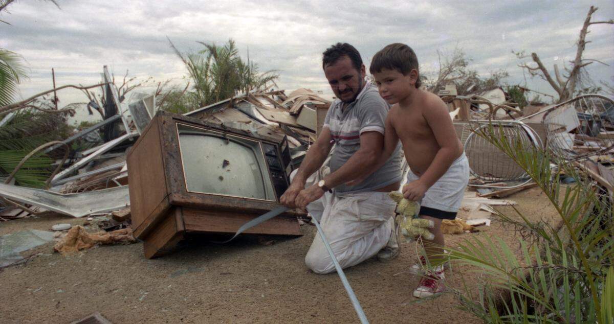 Armando Perez and son Lionel try to save belongings from demolished trailer.