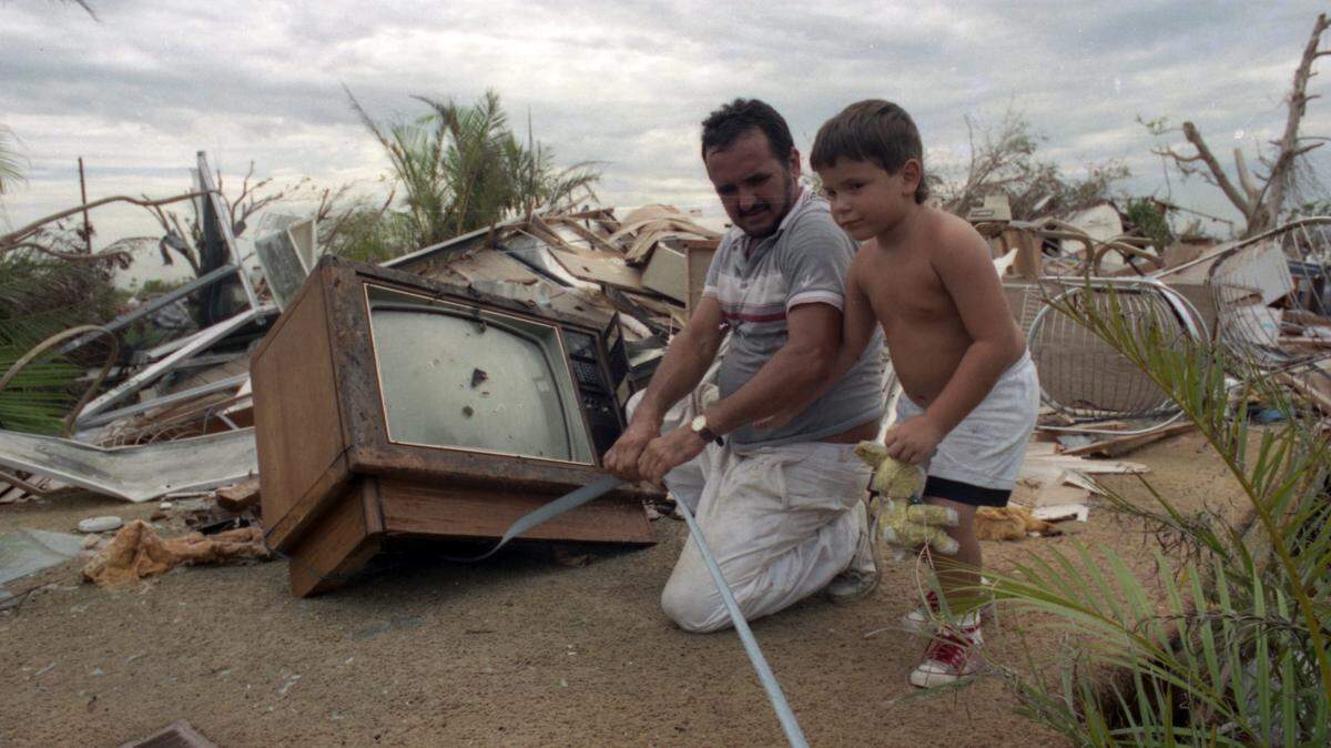 Armando Perez and son Lionel try to save belongings from demolished trailer.