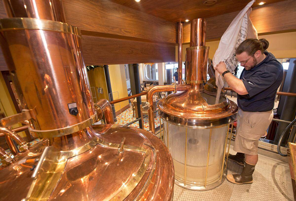 Carnival Vista Brewmaster Colin Presby pours malt into a mash tun located in the RedFrog Pub's brewery house onboard the Carnival Vista. Photo by Andy Newman/Carnival Cruise Line