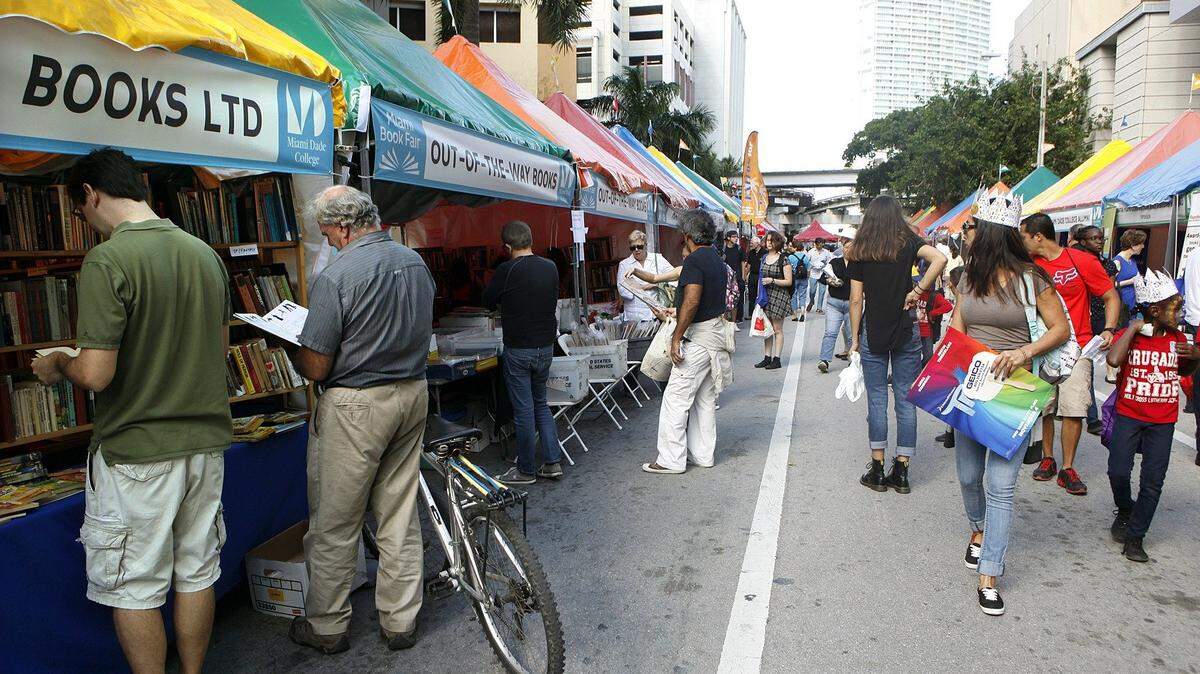 A man at left leans against his bike while checking out offerings at the Miami Book Fair's Street Fair.