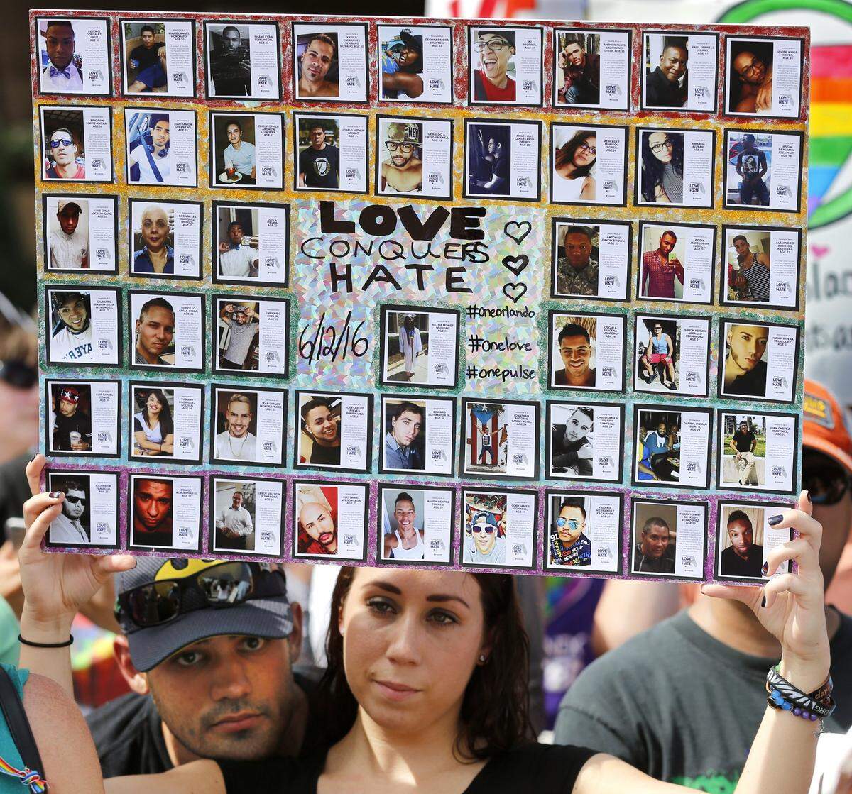Chris Fernandez and Samantha McHarg hold a poster of victims at Orlando rally outside a memorial service at the Cathedral Church of Saint Luke in support of shooting victims from Pulse night club on Saturday, June 18, 2016