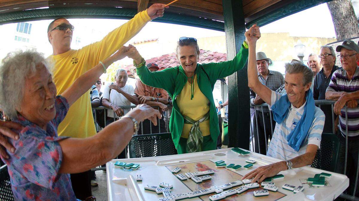 Mirta Sierra toma de las manos a los ganadores del segundo lugar del torneo de domino a la izquierda sentada La Cchina Choikelo Wong y Perfecto Diaz en el Parque del Domino de la Pequeña Habana durante el la decimoquinto edición del torneo de Domino del Carnval Miami hoy miercoles, 9 de marzo del 2016.