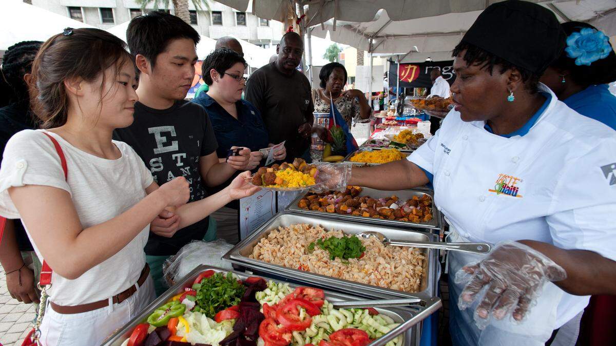 Eunyoung Lee, from Saint Louis, left, and Jae Won Lih, from Vero Beach, get a sampling of Haitian foods from Marthe LaFrance-Lubin, a chef with Leela's Restaurant, during the Taste of Haiti festival at the Museum of Contemporary Art plaza in North Miami, Saturday, May 11, 2013. The free event featured live music and scores of vendors of food, arts, crafts, and more.