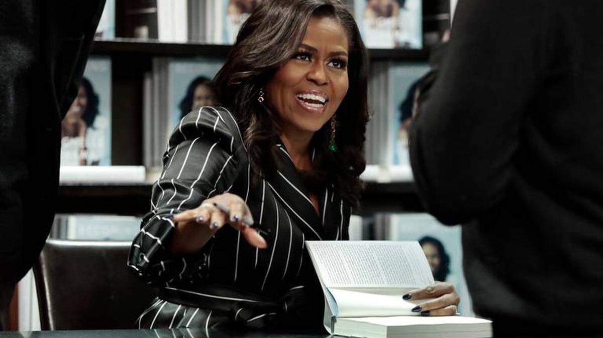 Former First Lady Michelle Obama signs books during an appearance for her book, “Becoming,” in New York. Sales for Obama’s memoir have topped 3 million and the former first lady is extending her book tour into 2019.