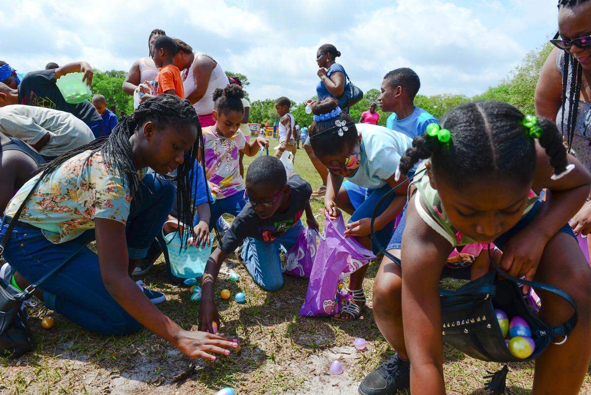 Kids rush to collect easter eggs that have fallen from a helicopter during the Miami Gardens annual Easter family fun day in Miami Gardens, Fla., on Saturday, March 26.