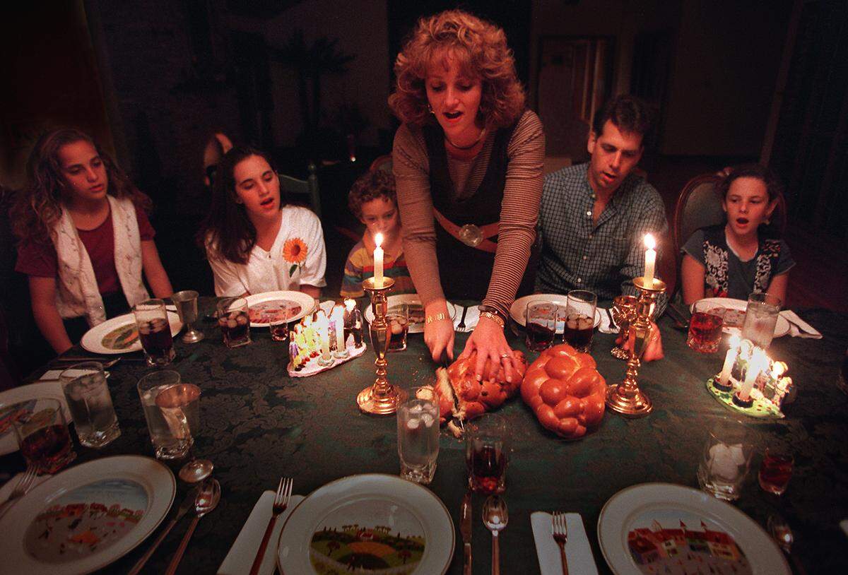THE ORSHAN FAMILY SINGS A BLESSING AS JODI ORSHAN (THE MOTHER) CUTS BREAD AFTER LIGHTING THE SHABBAT CANDLES BEFORE DINNER FRIDAY NIGHT( THE NAME OF THE BLESSING IS HaMOTVI). TO GO WITH STORY ON NEW JEWISH DEMOGRAPHIC  STUDY JUST RELEASED. FAMILY MEMBERS ARE FROM LEFT TO RT- SAMANTHA 12YRS; MELISSA 14YRS; JESSE 4YRS; JODI ( THE MOM); BOBBY (THE DAD); AND CARLY 9YRS. ALL WITH LAST NAME OFF ORSHAN.