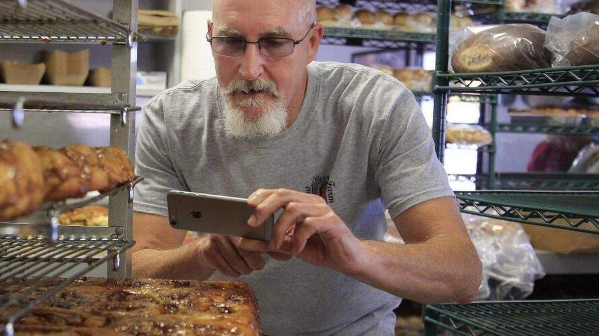 Thomas Blocher takes pictures with his cell phone of Knaus Berry Farm cinnamon rolls. CARL JUSTE
