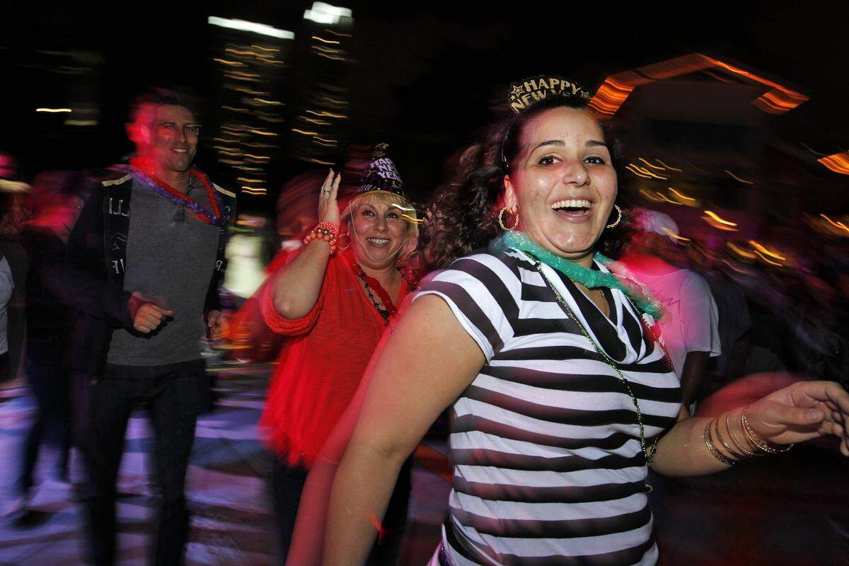 Ananay Rodriguez and Gina Perez dance at Bayfront Park as people gather to celebrate the New Year, 2013, with bands and fireworks. The Big Orange will asend to mark the the new year.
