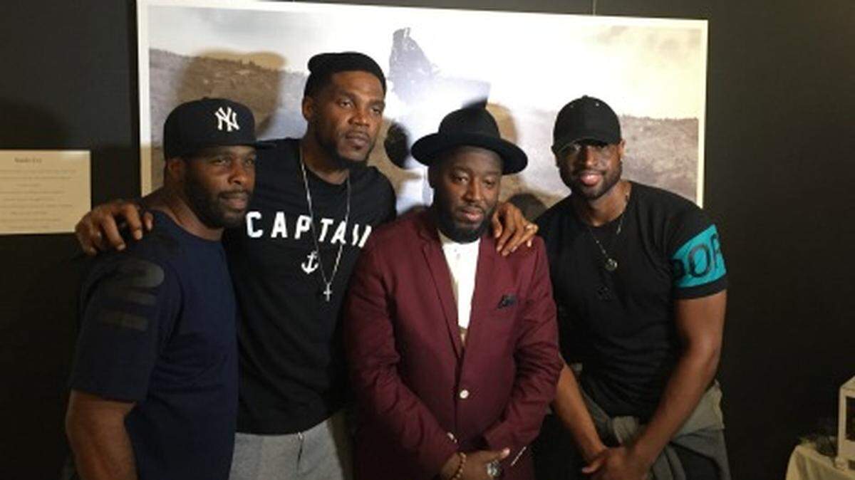 Photographer Bob Metelus (jacket) is greeted by Miami Heat forward Udonis Haslem (left) and former Heat star Dwyane Wade
