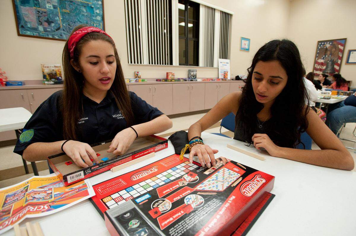 Christina Delgado, 14, an eighth grader at Miami Lakes K-8 Center and vice chair of the Miami Lakes Youth Activities Task Force, left, sets up a game of Scrabble with Angali Gonzalez, also 14 years old, during a board-game night at Mary Collins Community Center in Miami Lakes.