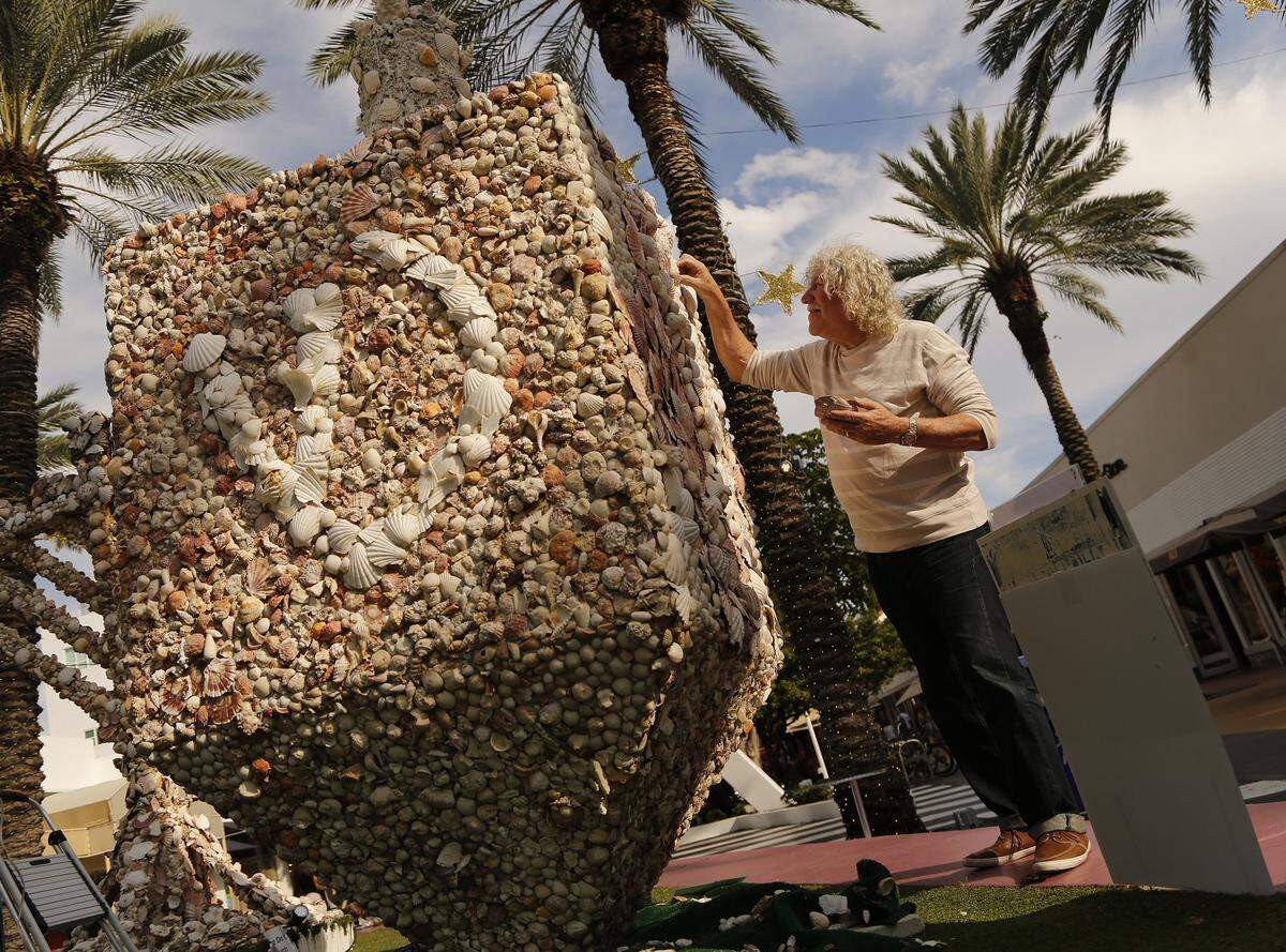 For the past 13 years, Roger Abramson has been adding seashells to his dreidel and menorah using over 35,000 shell according to the Abramson.  On December 15, 2014 Roger adds new shells as he replaces and repairs the large menorah and dreidel on display on Lincoln Road.