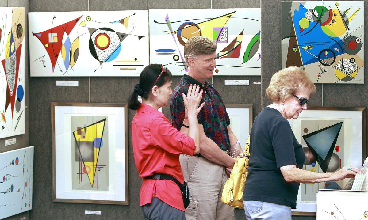 Boynton Beach artist Atsuko Okamoto, left, animatedly describes her geometric abstracts to Mark Glickman, center, and his mother Ricki Glickman on Saturday, Oct. 20, 2012 at the Las Olas Art Fair on Saturday, Oct. 20, 2012. The art fair -- celebrating its 25th anniversary -- continues Sunday along Las Olas Boulevard in downtown Fort Lauderdale.