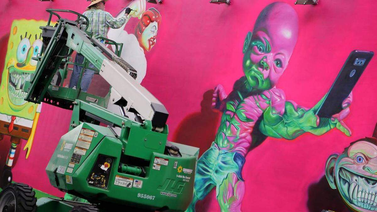 Street artist Ron English, from New York, is one of the many artists commissioned by Wynwood Walls. In this Nov. 29, 2018, photo, he works on his wall, which features the character “Temper Tot,” at the annual repainting, a precursor to the events of Miami Art Week coming Dec. 6-9 in Miami, Miami Beach and Wynwood.