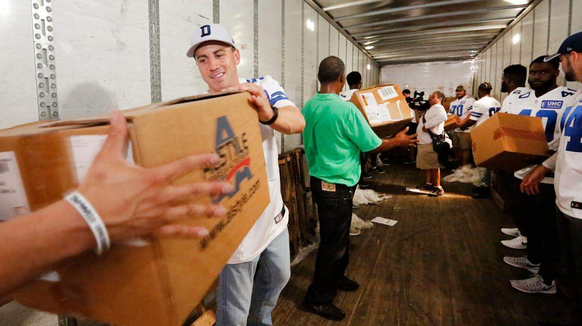 Dallas Cowboys kicker Dan Bailey, left, and fellow Cowboys help unload approximately 300,00 pieces of donated apparel from a tractor trailer at The Salvation Army Adult Rehabilitation Center Thursday, Aug. 31, 2017. The clothing items were donated to aid Hurricane Harvey evacuees who are sheltering in North Texas. (Ron Baselice/The Dallas Morning News via AP)
