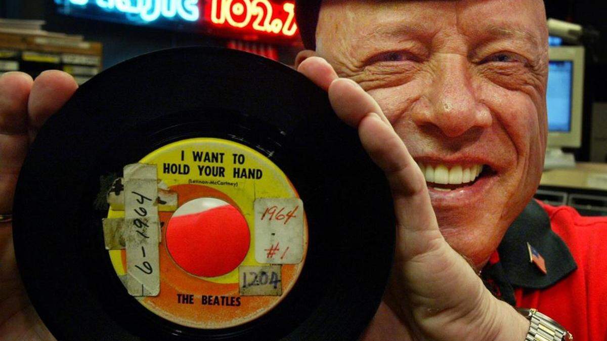 DJ Rick Shaw holds up the original 45 of the first Beatles hit he played on South Florida radio, “I Want to Hold Your Hand,” in 1964. While at Majic 102.7 in 2004, he celebrated its anniversary.
