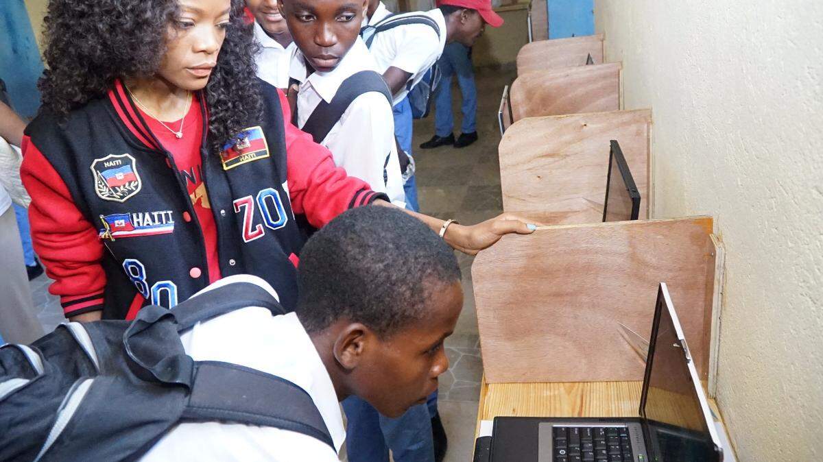 Wanda Tima with students in Haiti checking out their new computer lab thanks to a charity bowling tournament held by L'Union Suite.