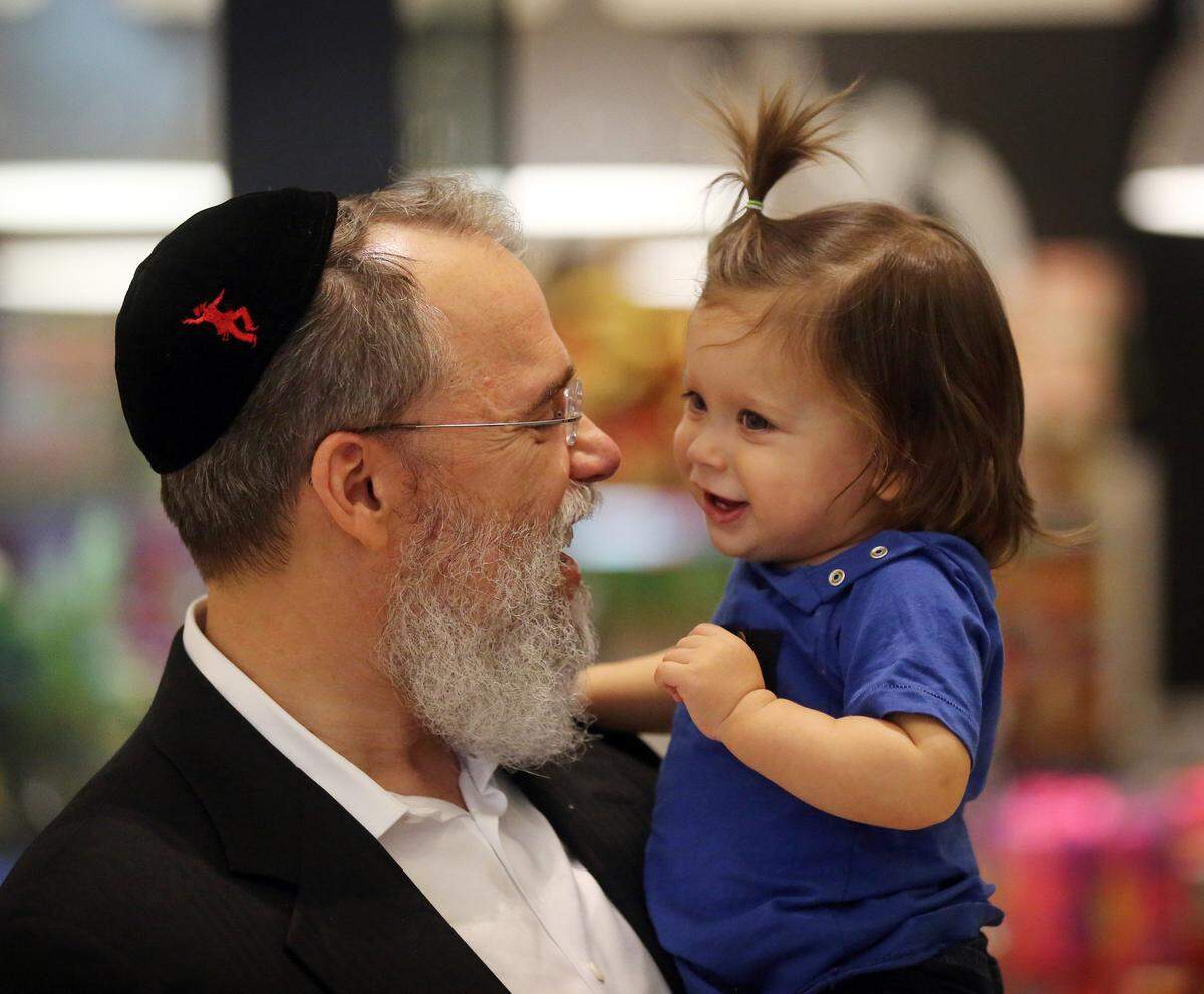 Zalman Fellig enjoys time with his grandson, Joe Joe, age 9 months, during a celebration of The Festival of Lights at a public Menorah Lighting ceremony on Thursday, Dec. 18, 2014.