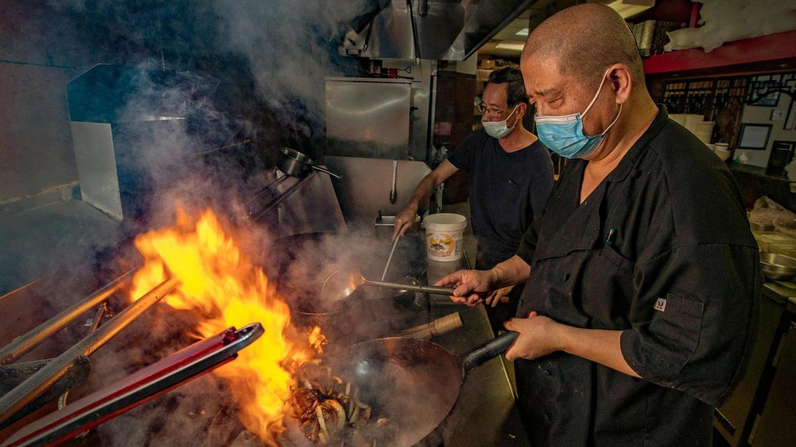 Chef Ming, in front, and Chef Wai cook using woks at a Venezuelan Chinese restaurant named Qianlong Asian Bistro in Doral. The restaurant was founded several years ago in Venezuela, where it was called El Palmar. Today, owner Yony Moy runs the fourth generation family restaurant on Tuesday, May 11, 2021.