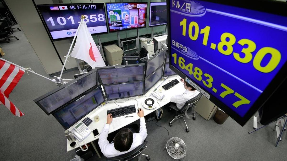 Money traders watch computer screens under the display showing the day's exchange rate between yen and the U.S. dollar, top, and Nikkei stock index, bottom, at a foreign exchange brokerage in Tokyo, Wednesday, Nov. 9, 2016. Asian shares have shed early gains, tumbling Wednesday as Donald Trump gained the lead in the electoral vote count in the presidential election. Dow and S&P futures also plunged. Earlier, investors had appeared persuaded that Hillary Clinton, seen as a more stable choice, would prevail.