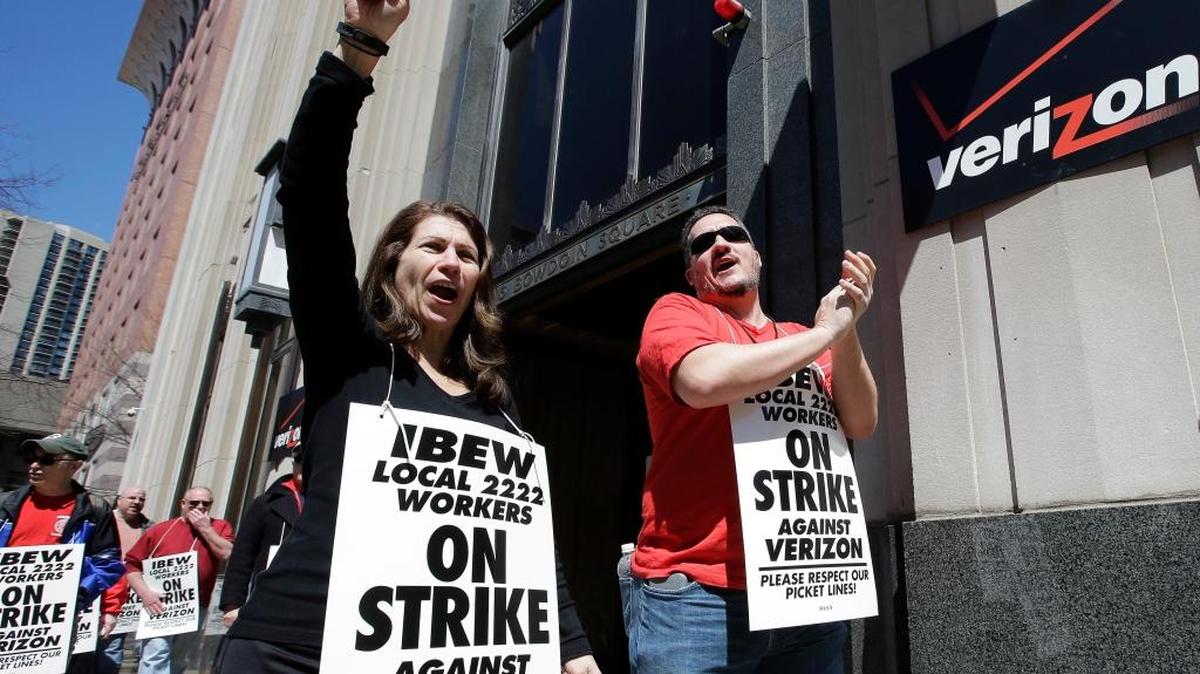 In this April 13, 2016 file photo, Verizon workers picket outside one of the company's facilities in Boston.