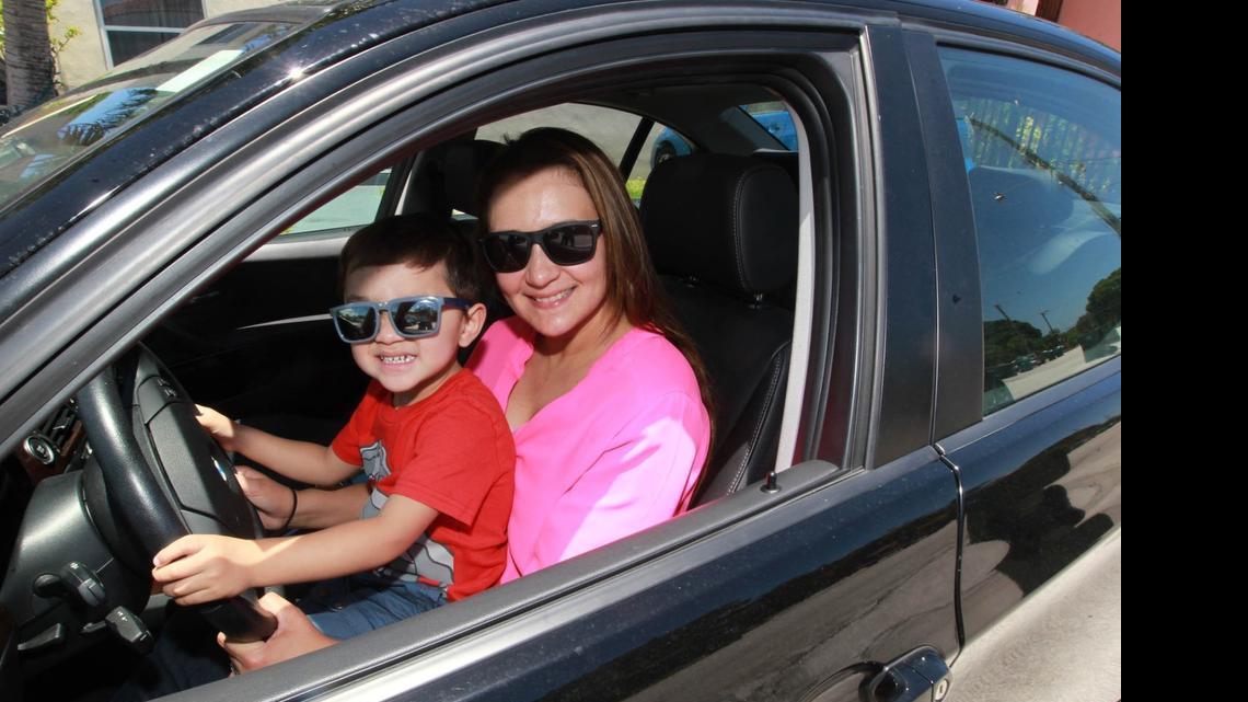 
Carolina Arguello, 38, and her 2-year-old son Andre Sarmiento sit in the 2011 BMW she uses as a driver-operator for uberX. 
