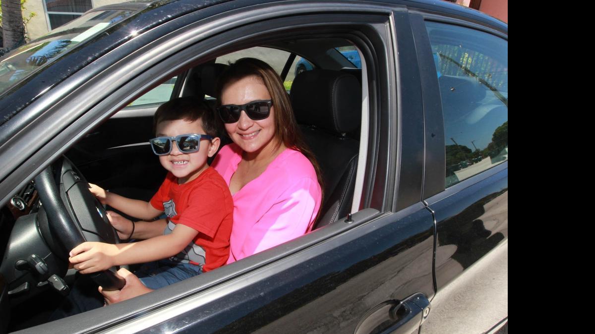 
Carolina Arguello, 38, and her 2-year-old son Andre Sarmiento sit in the 2011 BMW she uses as a driver-operator for uberX. 
