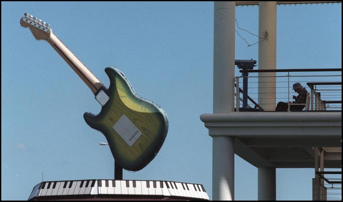 A man eats lunch with a view of the the giant guitar and keyboard atop the Hard Rock Cafe at Bayside Marketplace.