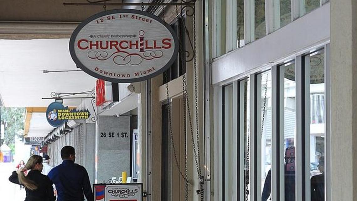 A couple walk pass two neighboring stores downtown - Churchill's Barber Shop that caters to locals and is doing well, and Metro Beauty Center, a beauty storewhere sales are suffering due because of the downturn in Latin America and a strong dollar. Both stores are owned by Jose Goyanes, a downtown businessman.