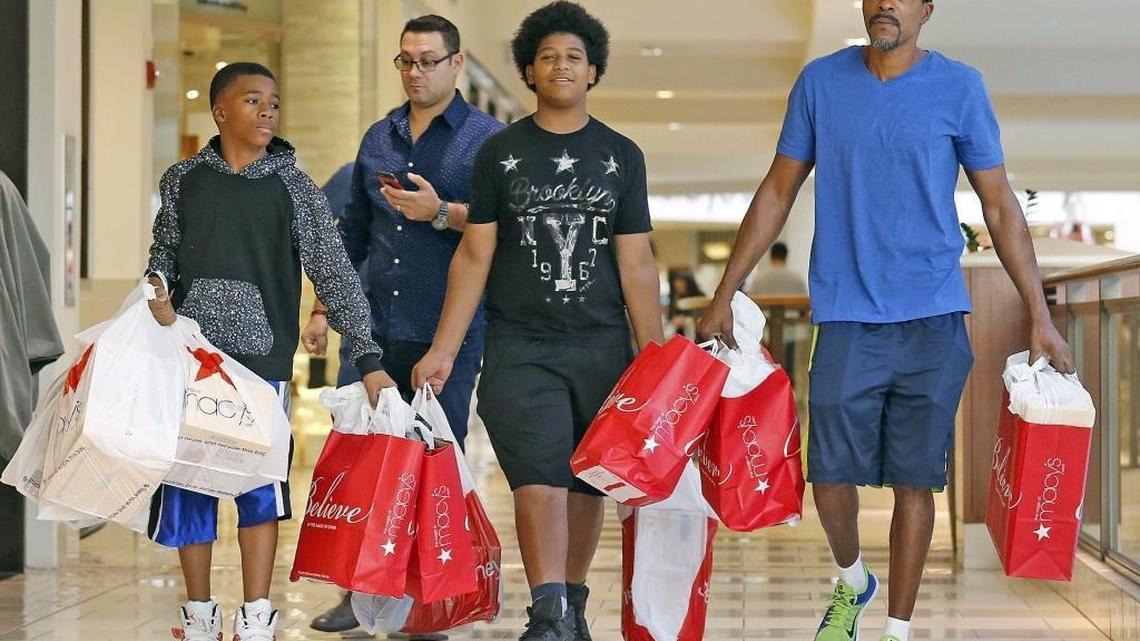 Jamarion Reid 12, and his brother Jhamauri 13, with their step-father Reggie Hawkins (hat), carry 16 shopping bags through the mall after a morning of shopping on Black Friday at Aventura Mall, November 27, 2015.