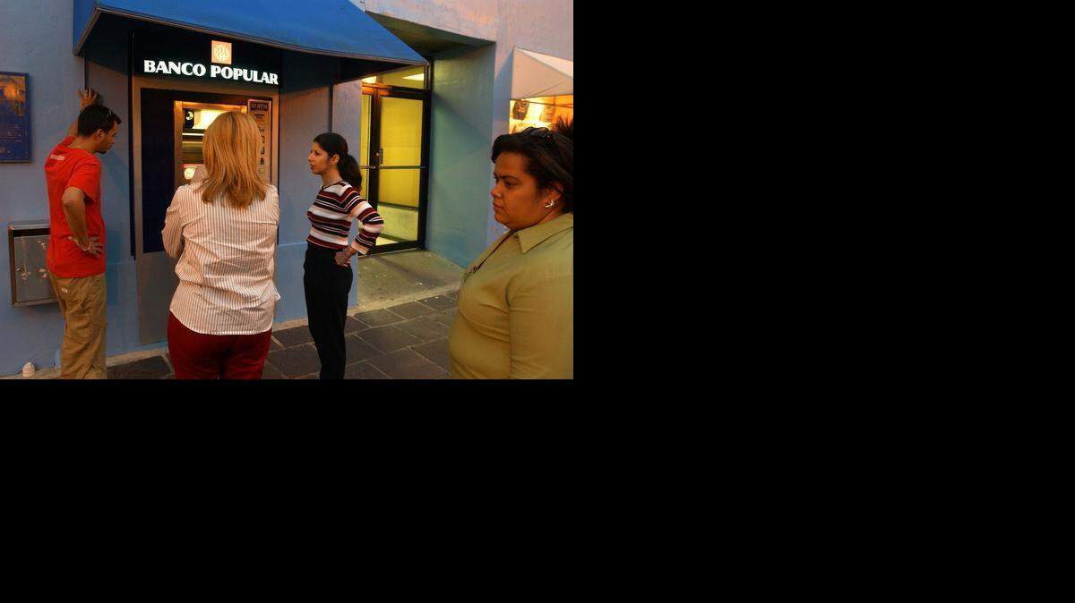 
People stand in line for a Banco Popular teller machine in San Juan, Puerto Rico.
