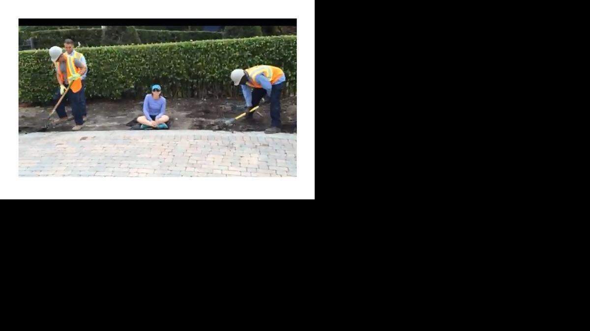 
An image from video shows Dara Clarke sitting while workers build a sidewalk around her near her home at the Island Estates in Aventura.
