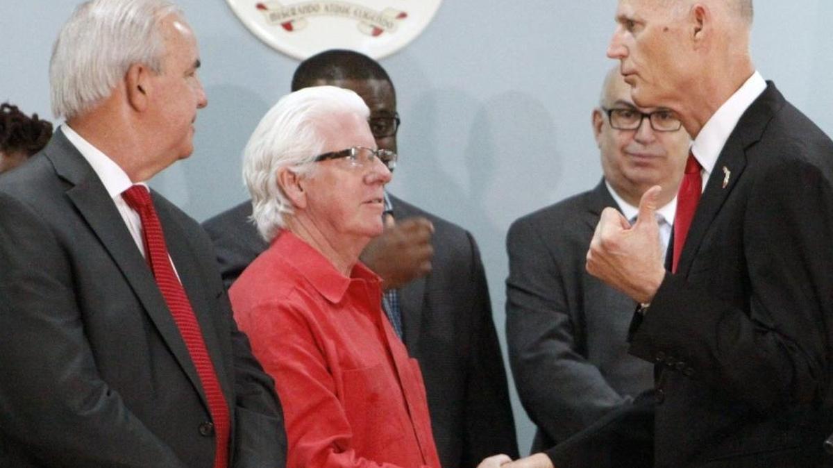 After announcing he lifted the zone of active Zika transmission in one square mile of Miami's Little River neighborhood, Gov. Rick Scott, right, shakes hands with William D. Talbert, III, president and CEO of the Greater Miami Convention & Visitors Bureau, center. At left is Miami-Dade County Mayor Carlos Giménez. The announcement was on Friday morning, Dec. 2, 2016 at St. Mary Cathedral School, 7485 NW Second Ave., Miami.