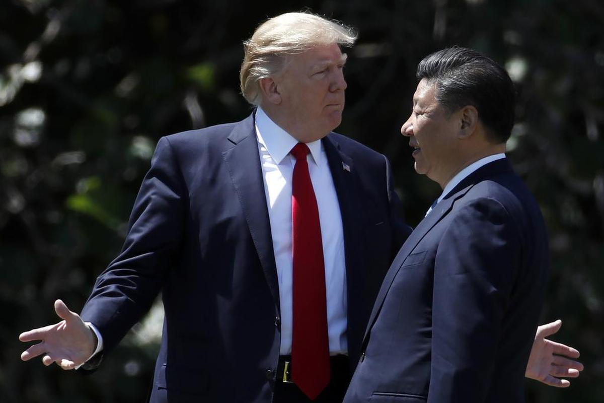 In this April 7, 2017, photo, President Donald Trump gestures as he and Chinese President Xi Jinping walk together after their meetings at Mar-a-Lago, in Palm Beach, Florida.