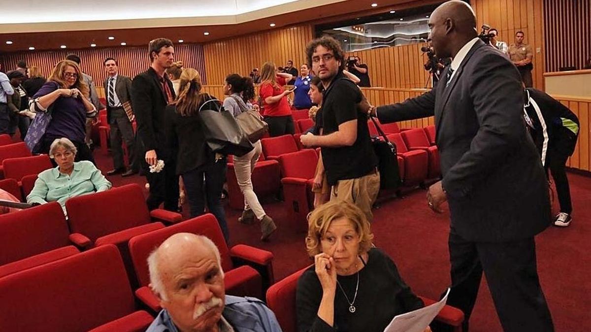 An activist, Tomas Kennedy, is pushed back after he threw his white flower toward the commissioners after the commission’s vote to back Mayor Carlos Gimenez to end Miami-Dade status as a sanctuary city on Friday, February 17, 2017.