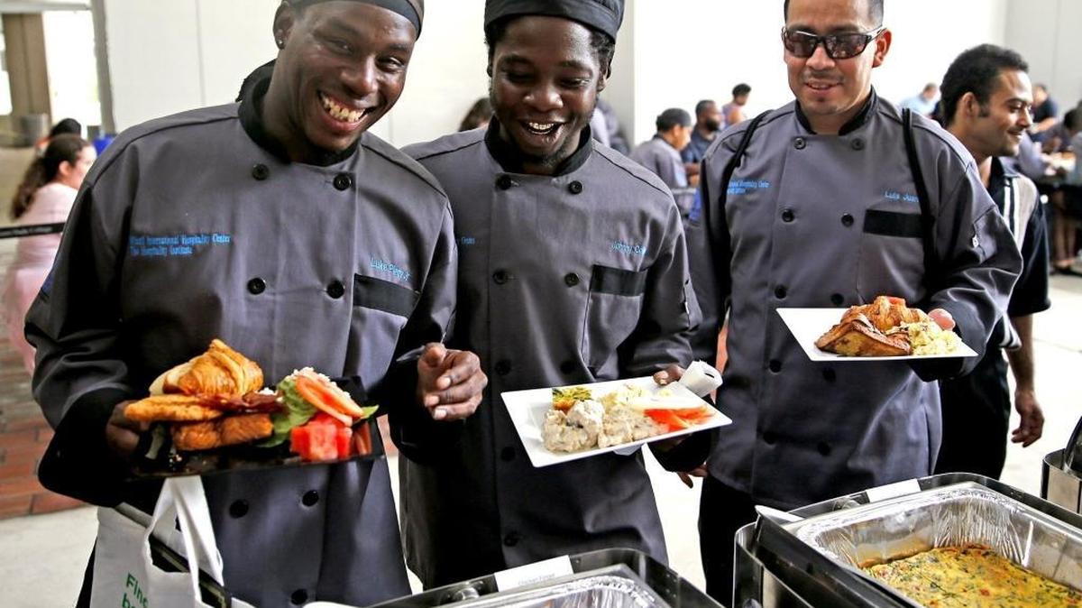 Students Luke Pierre Jr, Johnny Collins, and Luis Jarez eat from the buffet their class cooked for their graduation from the Hospitality Institute, a tourism education program at Miami-Dade College, on Sept. 28. The Overtown-based program focuses on providing educational opportunities for people in underserved communities who want to learn skills for entry-level tourism jobs.