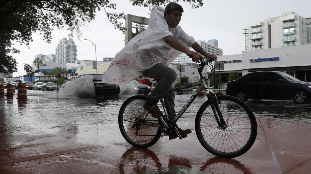 A cyclist rides on the sidewalk alongside heavily flooded streets as rain falls on Sept. 23, 2014 in Miami Beach. National and regional climate change risk assessments have shown that the area is vulnerable to rising sea levels.