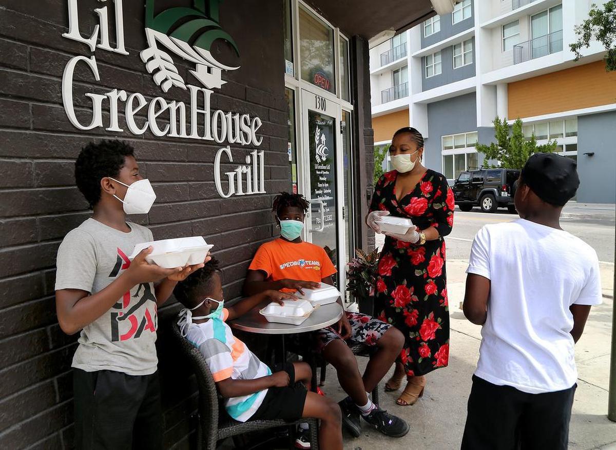 Owner Nicole Gates distributes free food to kids living around the Lil Greenhouse Grill restaurant in the Overtown area. The restaurant continues to operate on a limited basis, selling meals for pickup and delivery, and also providing relief to their communities during the economic and health crises caused by the coronavirus. on Tuesday, April 29, 2020.