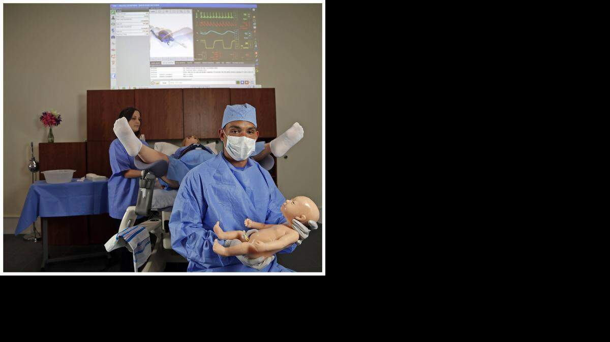 
BUNDLE OF JOY: Christopher Jorge, product specialist, holds the infant simulator after the demonstration by the simulator, “Victoria,” with help from Susana Pereda. 
